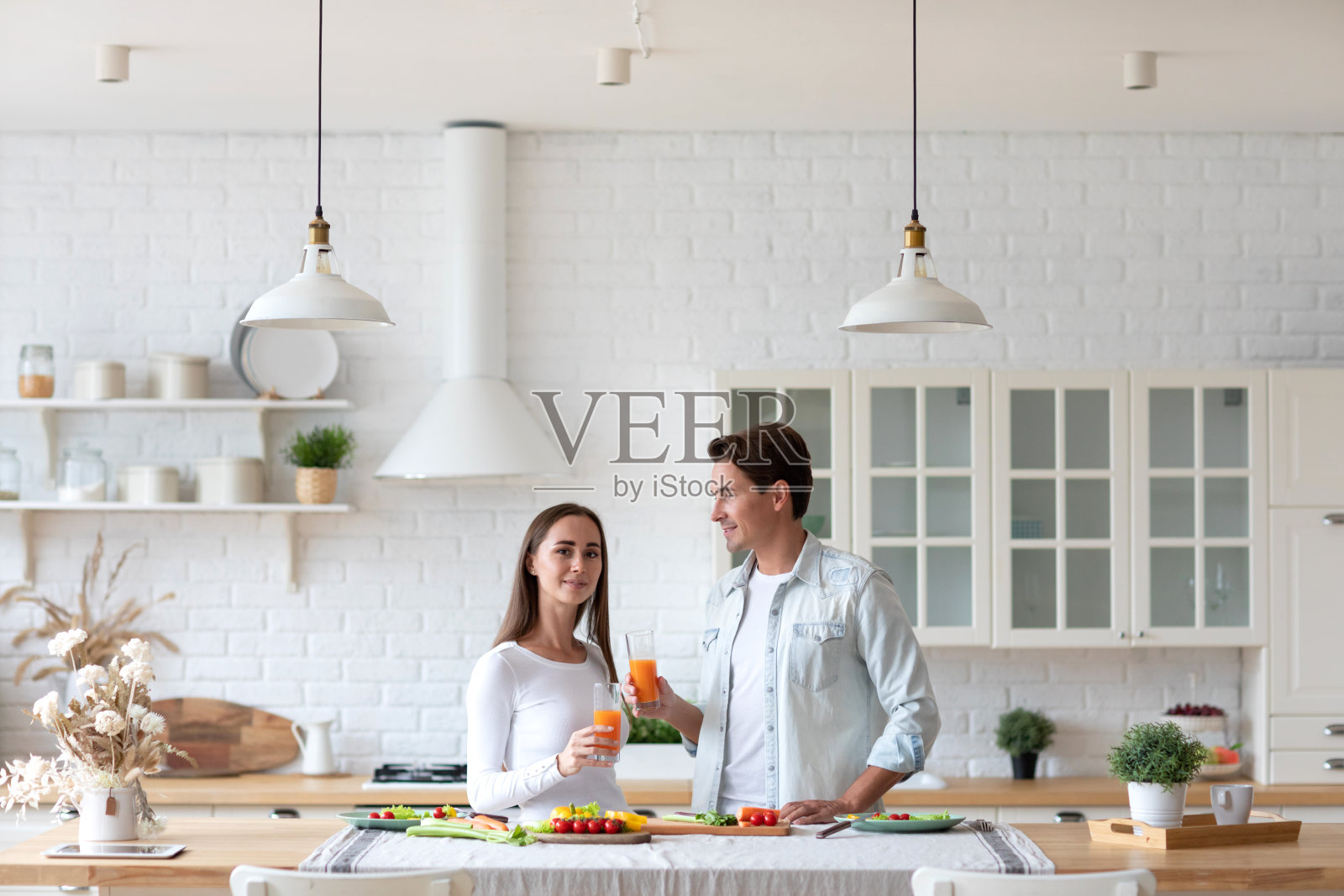 年轻漂亮的夫妇和果汁站在厨房。健康饮食，共度时光照片摄影图片