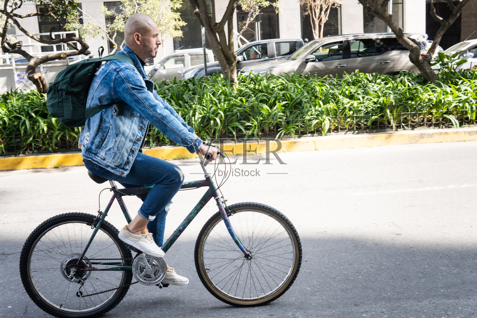 一个穿着休闲的秃头年轻人在城市里骑着自行车照片摄影图片