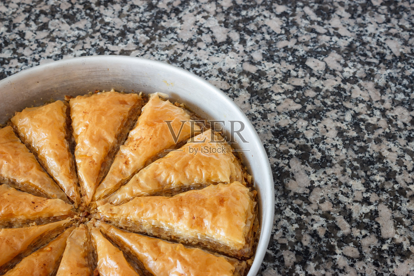 传统的土耳其甜点果仁蜜饼在灰色大理石背景的圆形托盘上。照片摄影图片