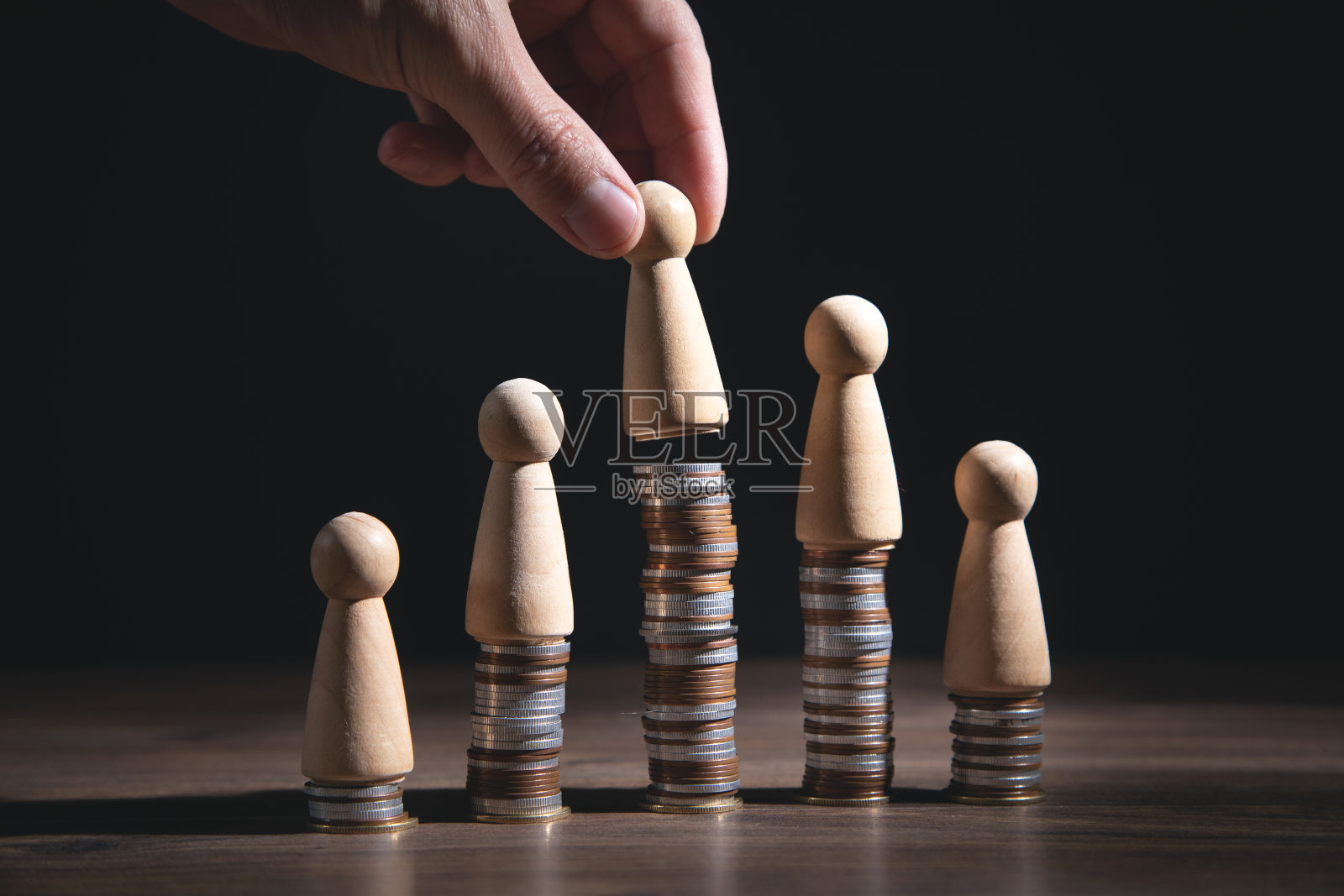 男性手显示木制的人在硬币堆栈上。照片摄影图片