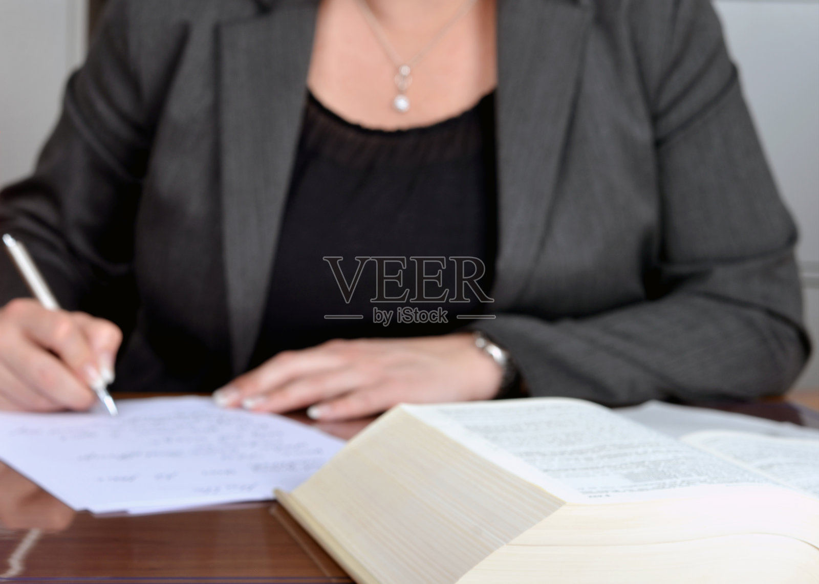 模糊剪影一个成功的女商人穿着黑色和灰色的职业装做文书工作的细节，选择性的焦点，背景照片摄影图片