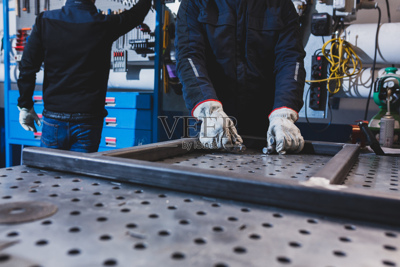 近距离的人的手工作在工作台与金属件。照片摄影图片