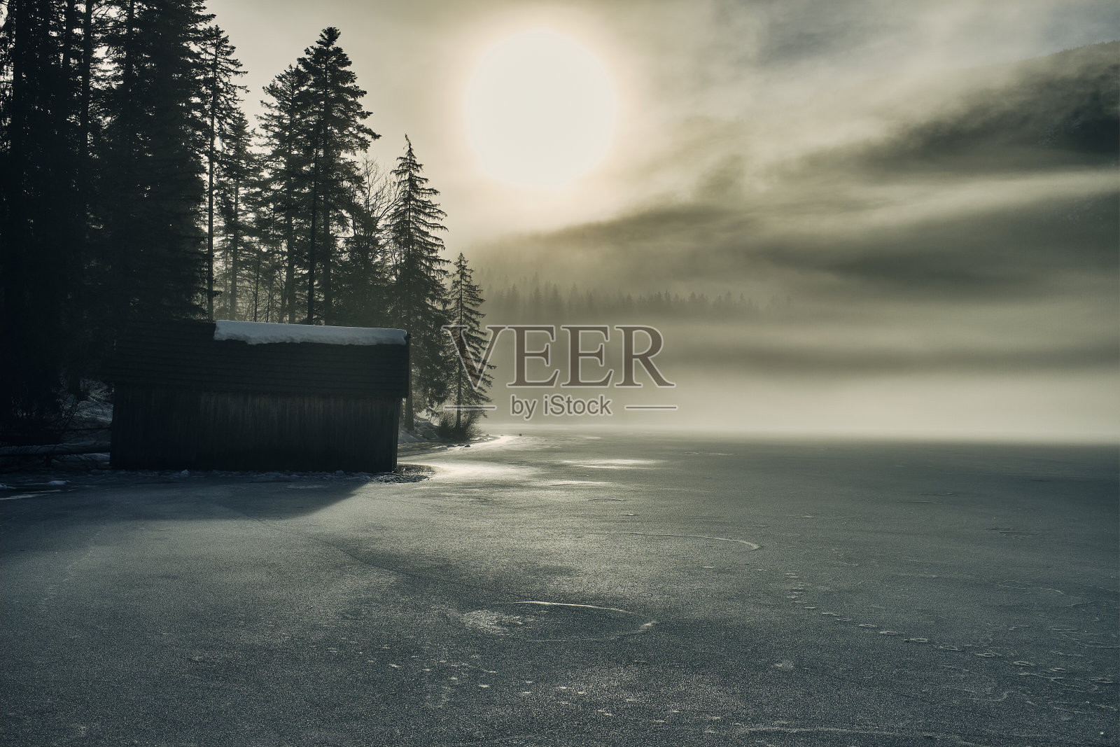 冰冻的奥登湖在寒冷的冬日，阳光透过一层雾照耀着。照片摄影图片