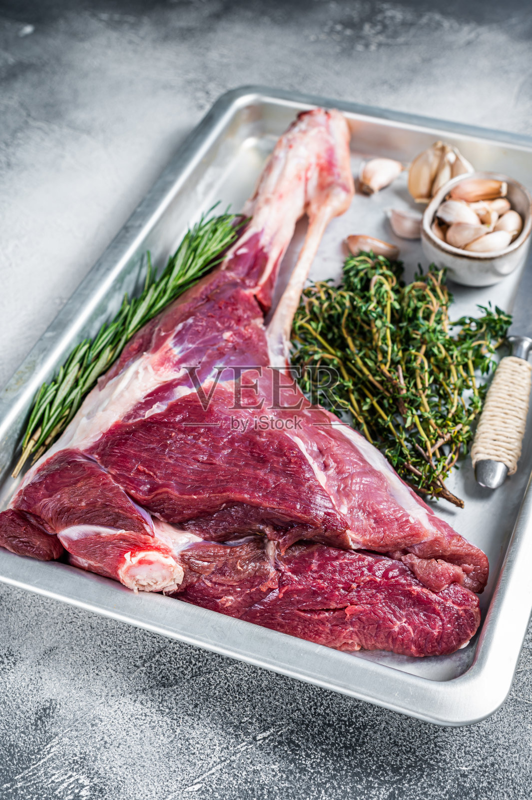 生的山羊腿或羊腿与香草烤盘。白色背景。俯视图照片摄影图片