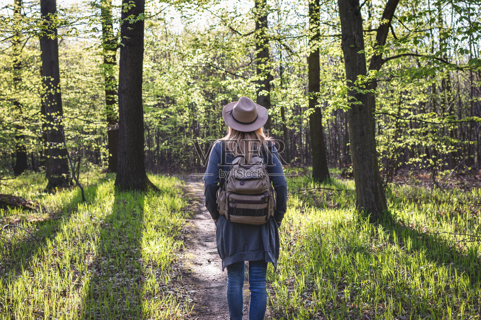 女性徒步旅行者走在林间小径在春天照片摄影图片