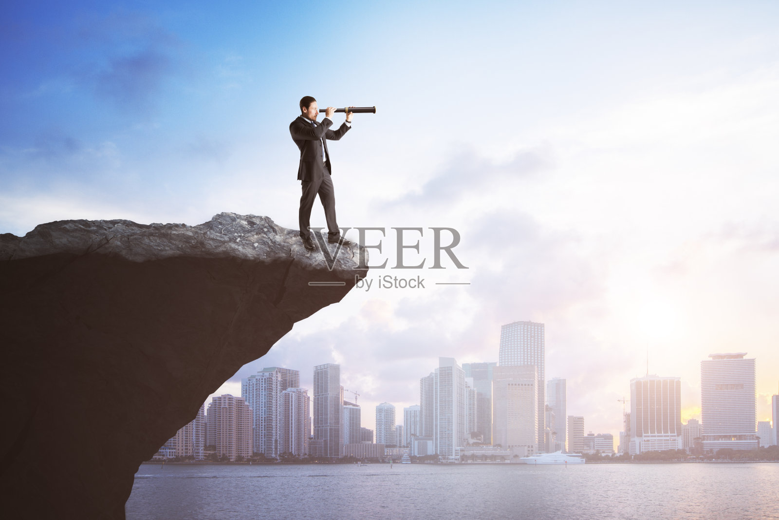 有吸引力的年轻欧洲人在悬崖边望远镜看向远处明亮的城市背景与日光和模拟的地方。未来、成功、领导力和职业成长理念。照片摄影图片