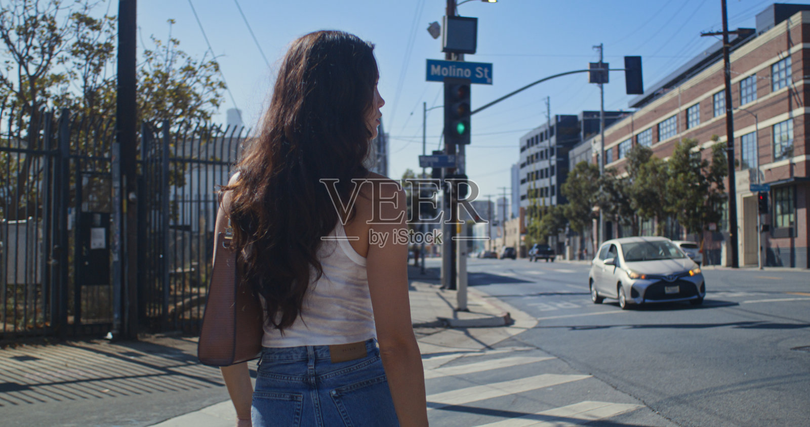 不知名的女士穿过马路的特写。时髦的长发女人走在人行横道上照片摄影图片