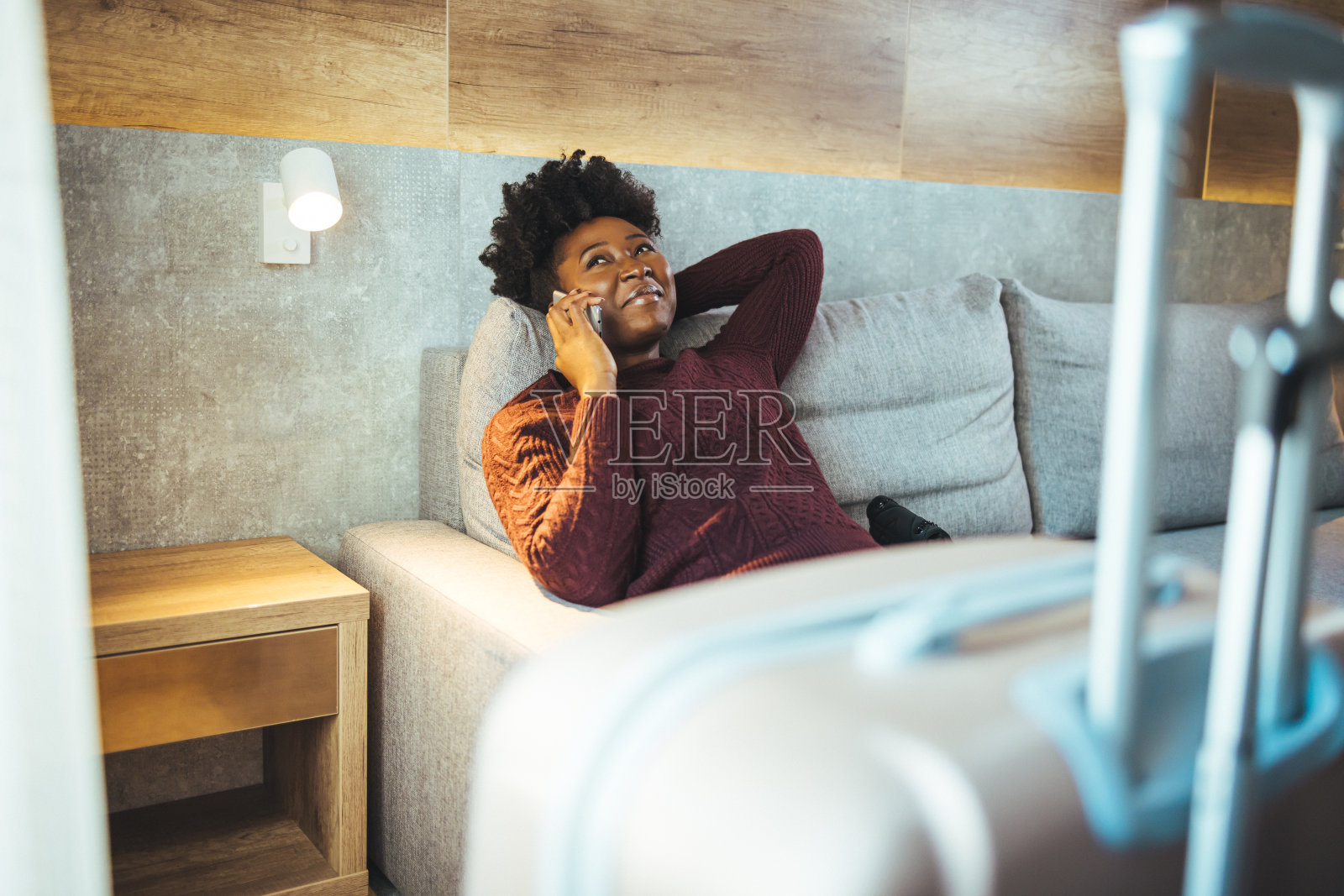 一个自信的女商人，穿着休闲装，在酒店房间里打电话，面带微笑。照片摄影图片