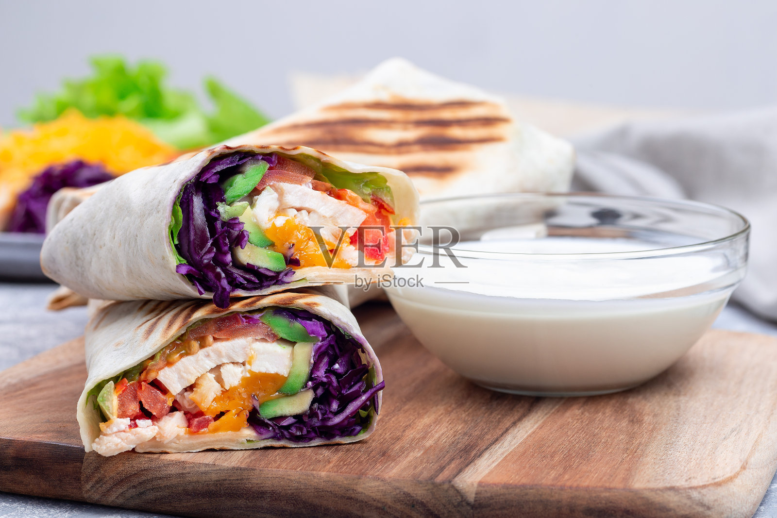 木板烤鸡卷配红甘蓝、牛油果、番茄、生菜和切达奶酪照片摄影图片