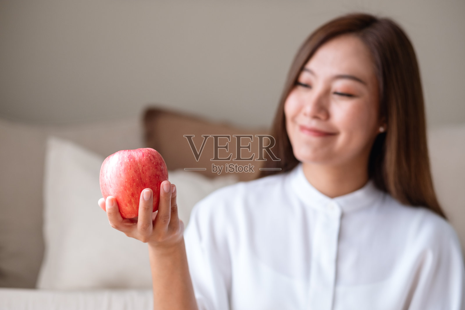 一个年轻女子的肖像，手里拿着一个红苹果，看着它照片摄影图片