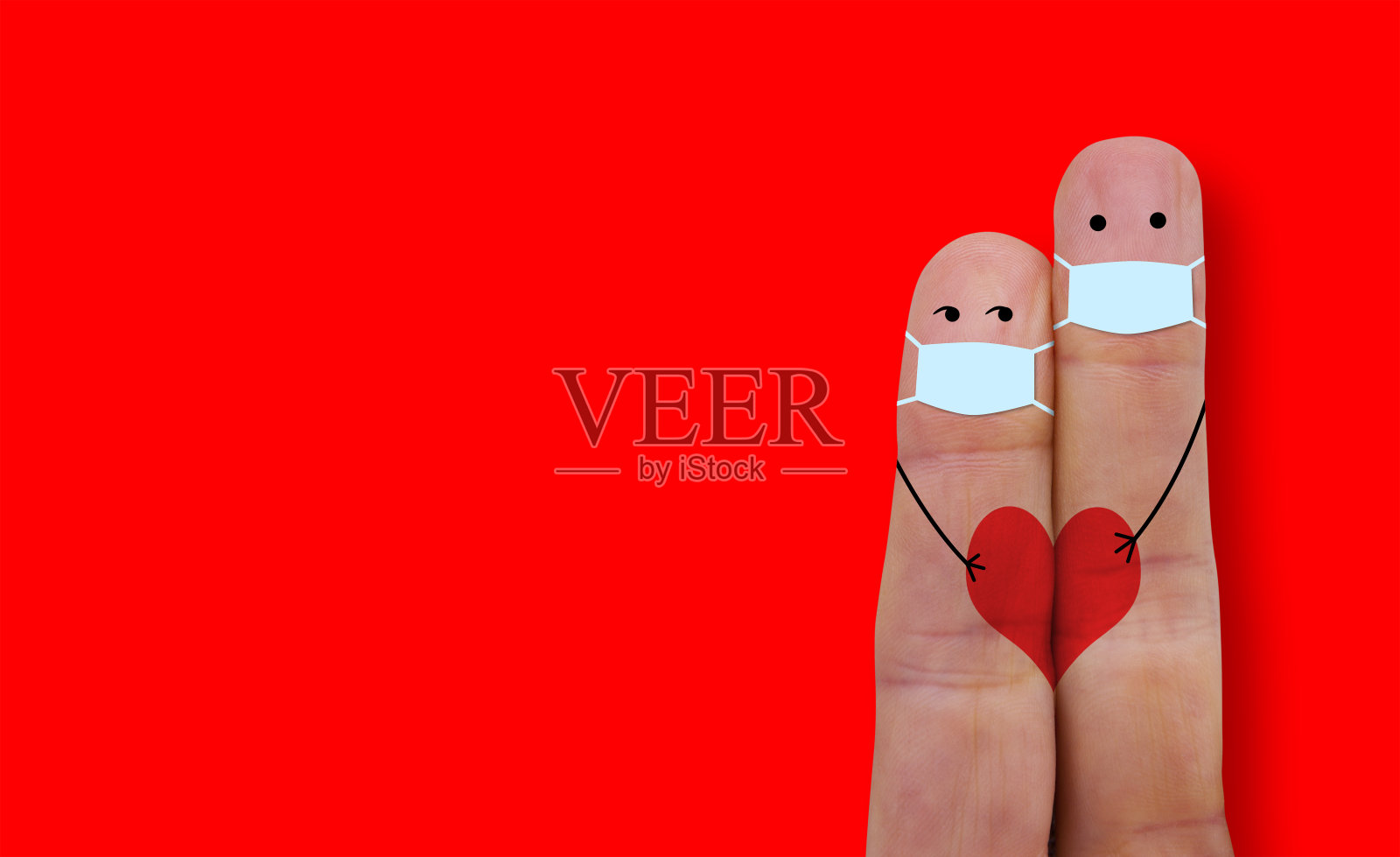 戴着口罩的情侣正在保护自己免受冠状病毒 Covid-19 的侵害。手指比心。照片摄影图片