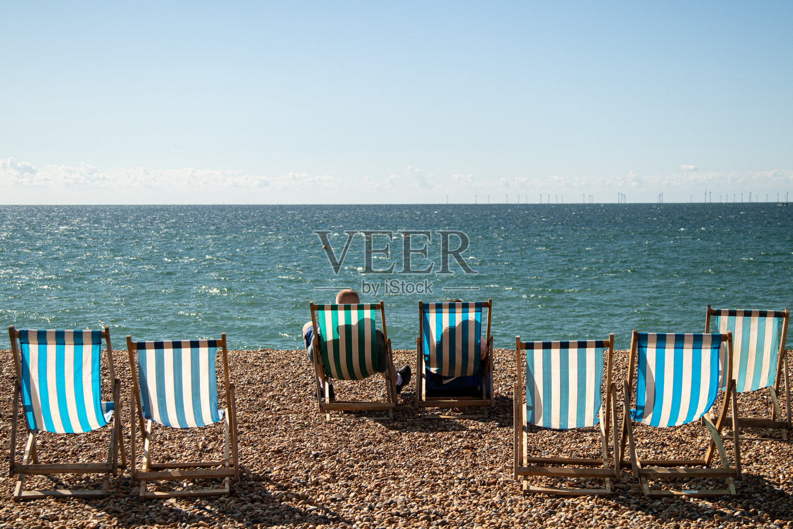 阳光明媚的一天，英国布莱顿海滩的条纹椅子照片摄影图片