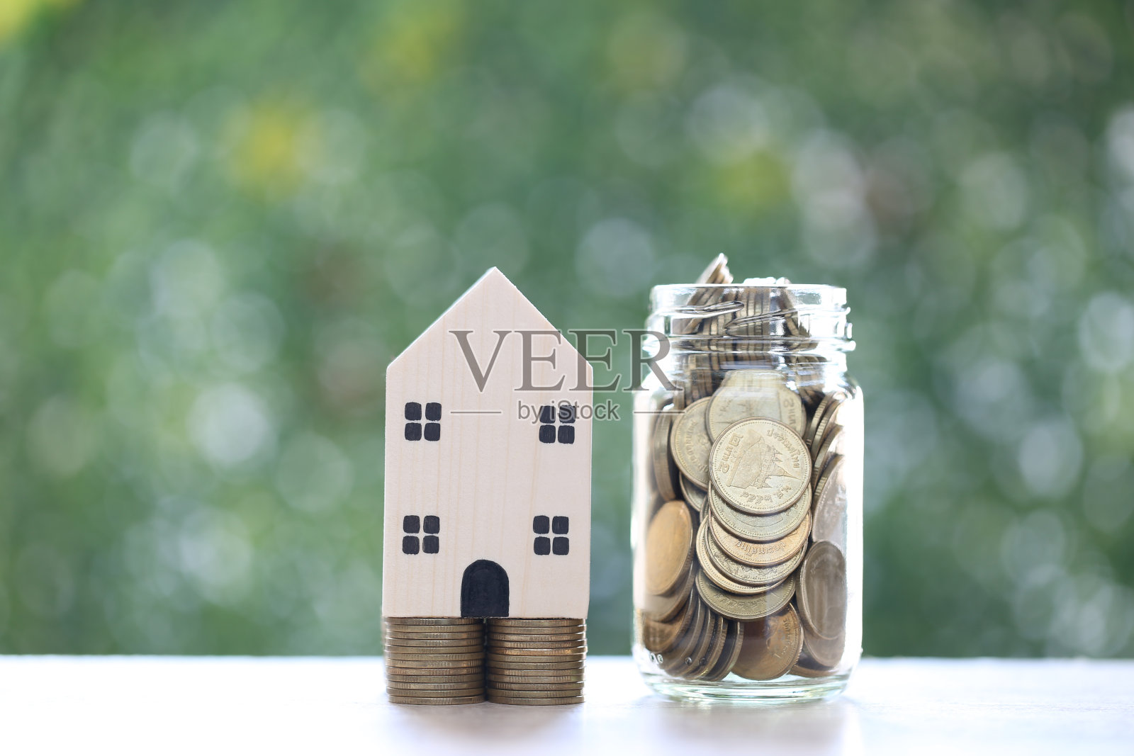 模型房子和叠硬币在玻璃瓶上的自然绿色背景，商业投资和房地产概念照片摄影图片