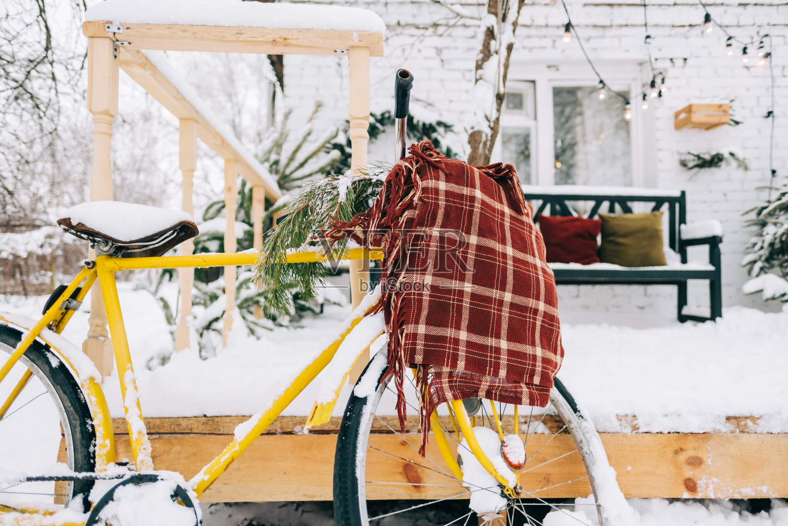 白雪覆盖的自行车在后院与针织格子。照片摄影图片
