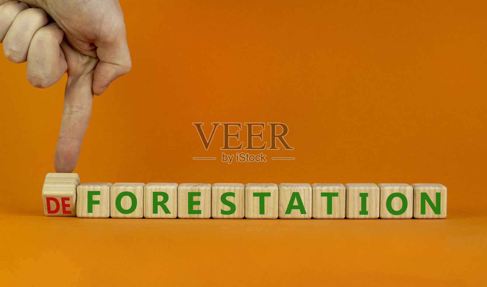 造林或毁林的象征。生态学家把木头方块变成了“森林砍伐”一词。橙色背景，复制空间。生态、造林或毁林概念。照片摄影图片