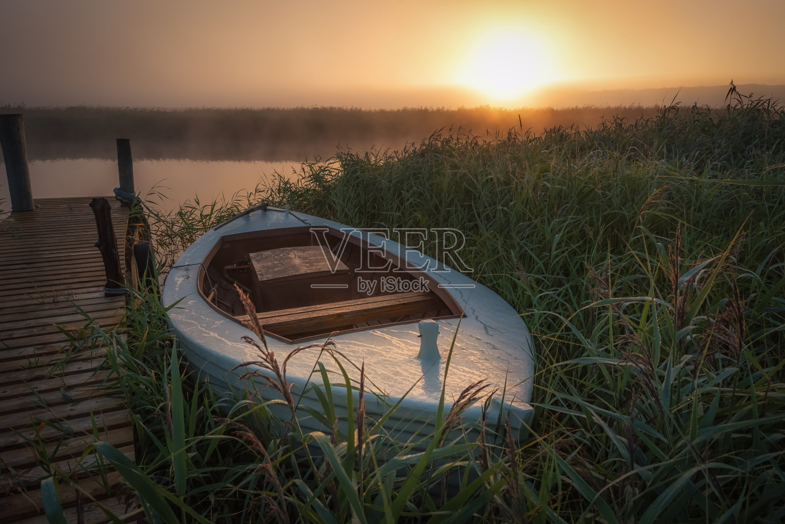 日出时码头上孤独的小船照片摄影图片