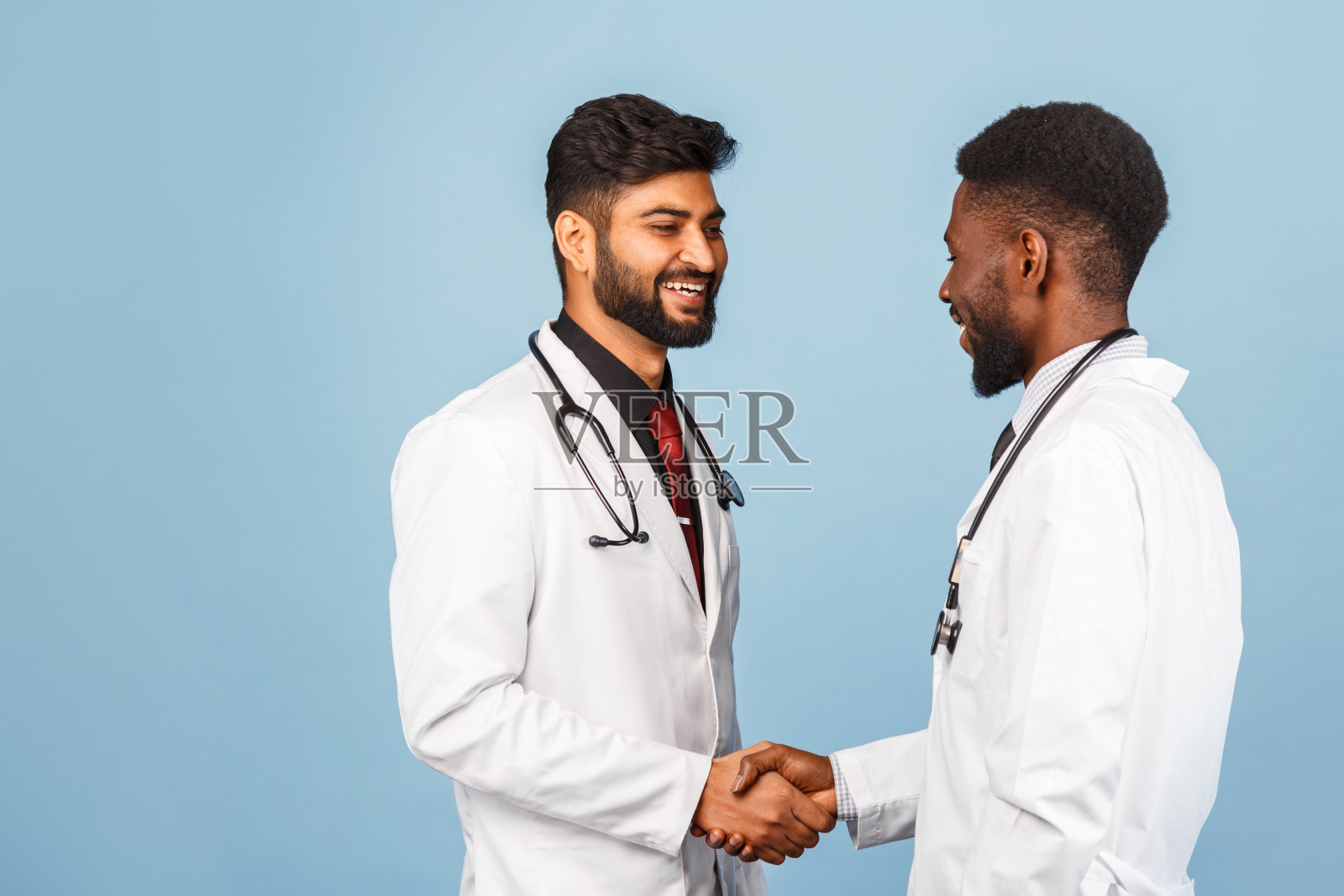 在蓝色的背景下，知识卫生保健专业人员与年轻医生讨论研究结果的白色实验室外套的损失肖像照片摄影图片