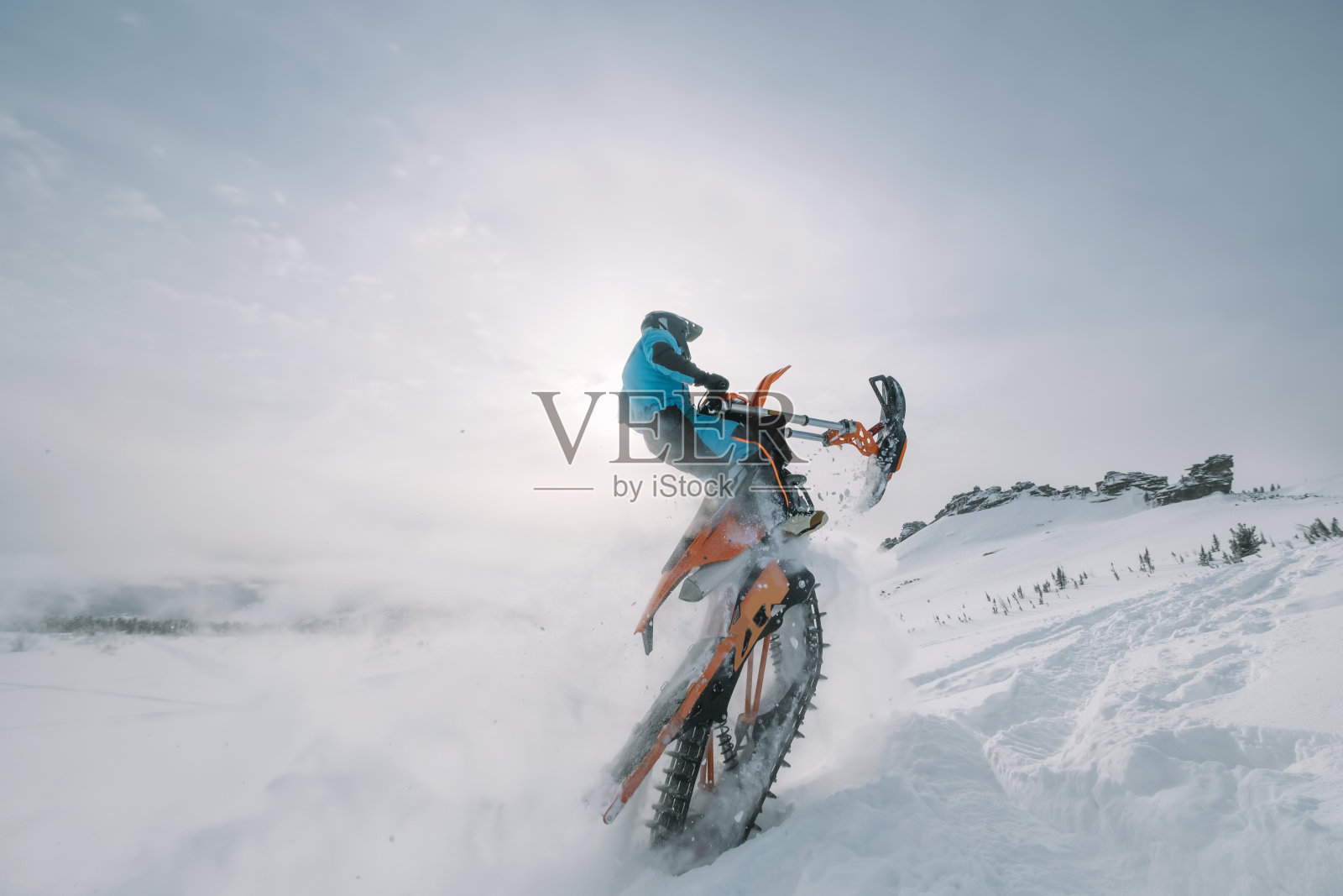 在美丽的雪粉和阳光的山谷里跳跃的雪车骑手。将摩托车改装成滑雪板和特殊的雪上赛道，而不是车轮照片摄影图片