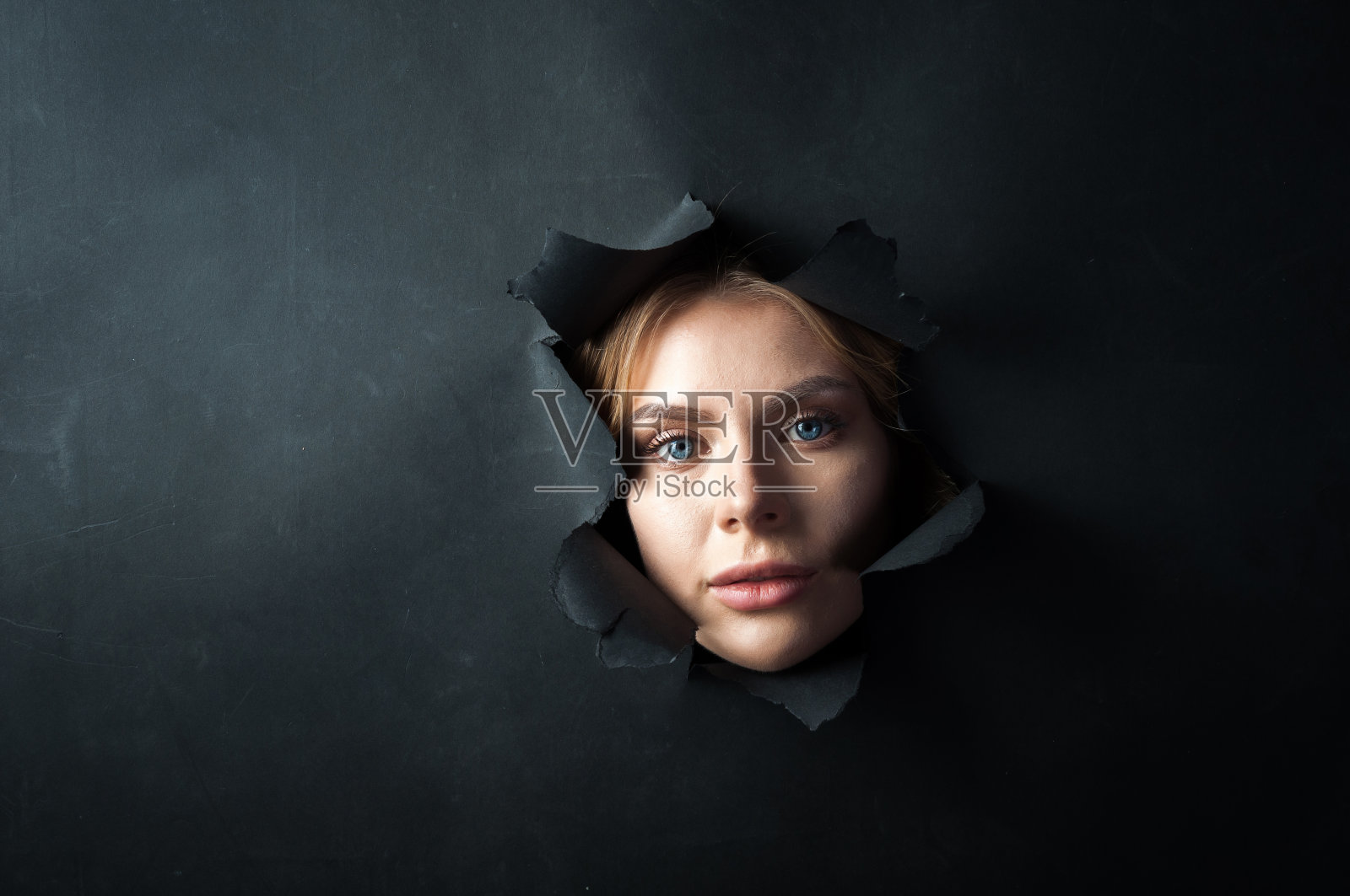 女孩的脸出现在黑色的背景上。照片摄影图片