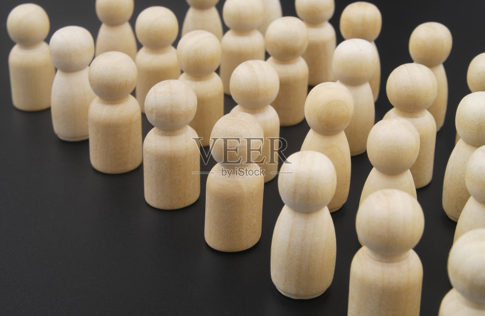 许多木制的人物在黑色的背景下彼此站在一起照片摄影图片