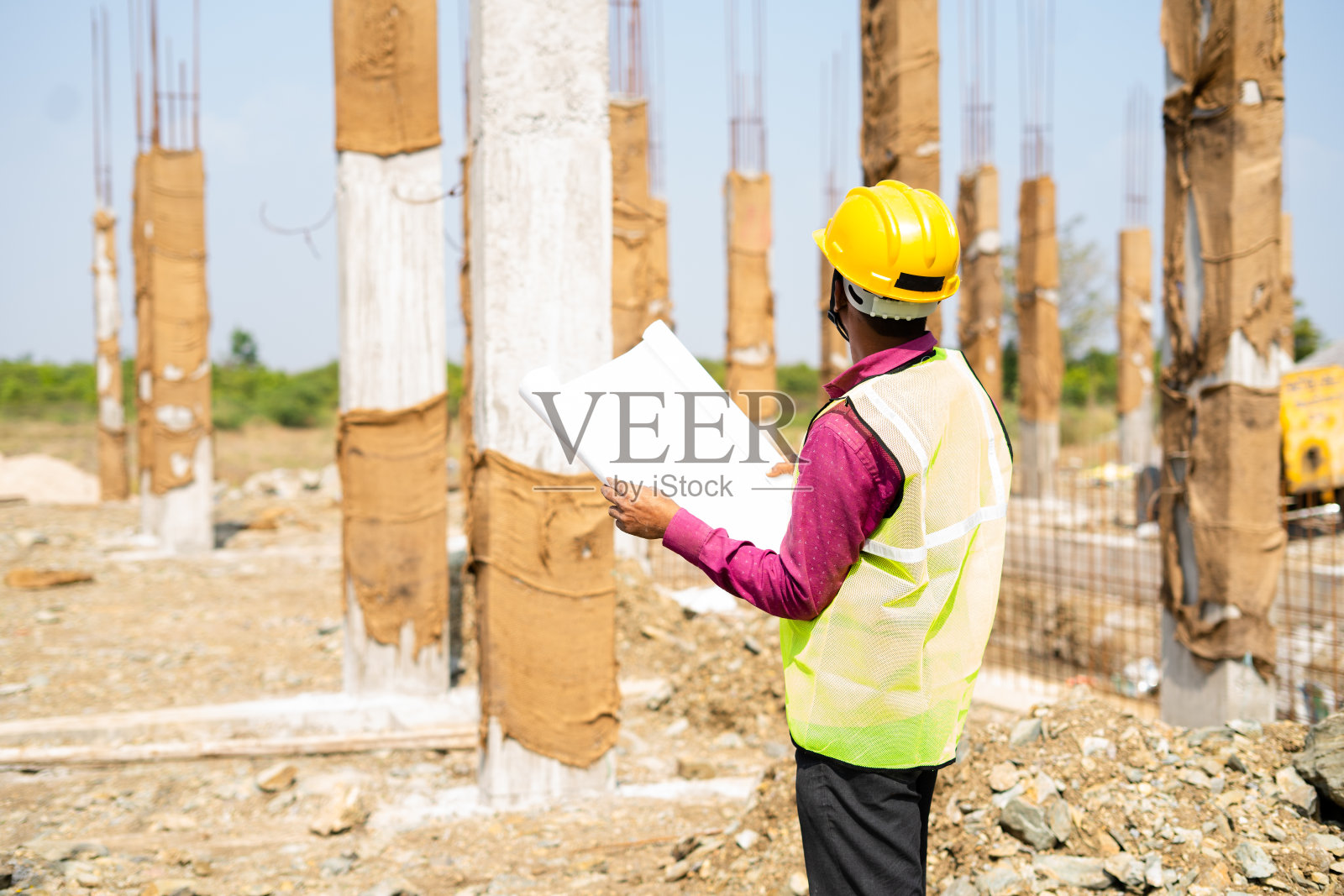 年轻的印度工程师或监工在工作场所检查施工计划——熟练劳动的概念、日常生活方式和施工服务。照片摄影图片