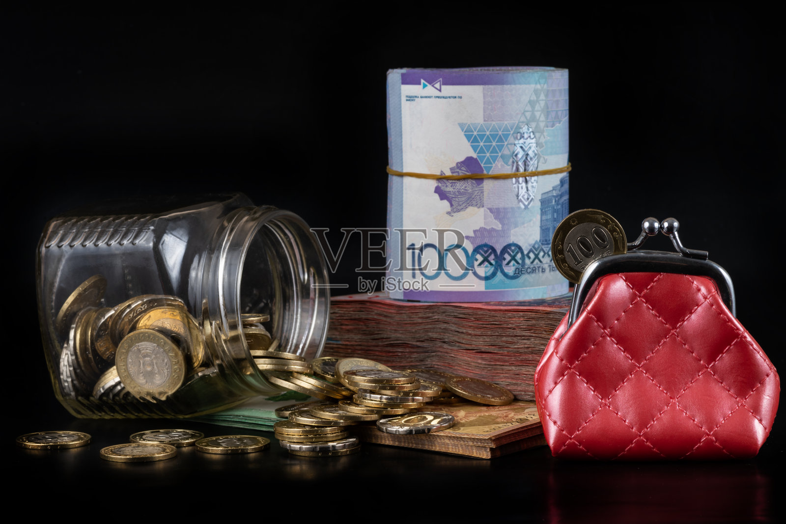 面值100和200坚戈硬币，红色钱包，玻璃罐和哈萨克黑底色钞票照片摄影图片