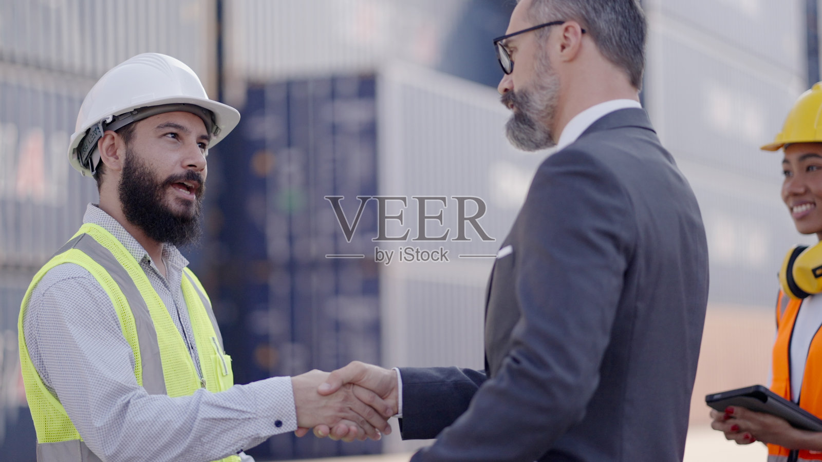 中年投资者或高管、经理与专业男工程师握手，在集装箱装载场共同处理工作成功或约定投资。工作完成时要握手表示祝贺。照片摄影图片