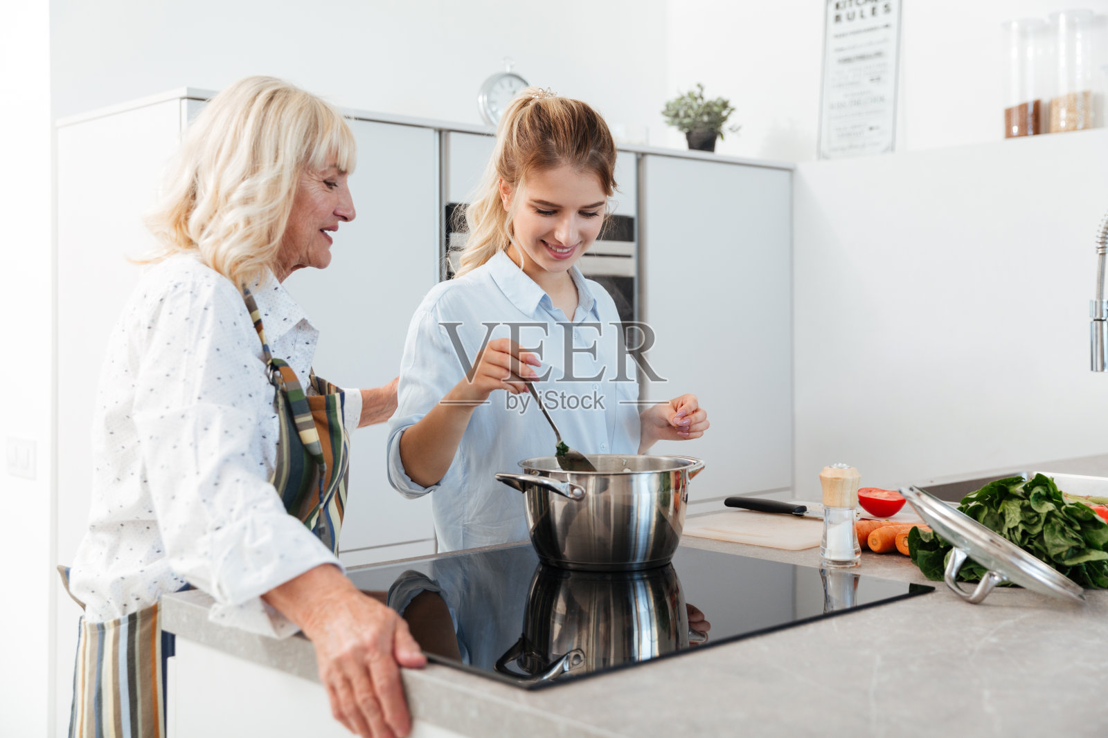 快乐的年轻女人和她的祖母一起做饭照片摄影图片
