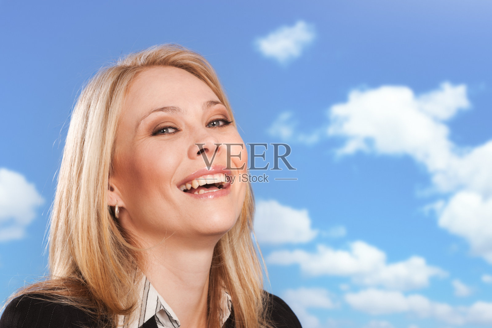 穿着西装的金发女人笑着看着镜头，背景是可爱的夏日天空照片摄影图片