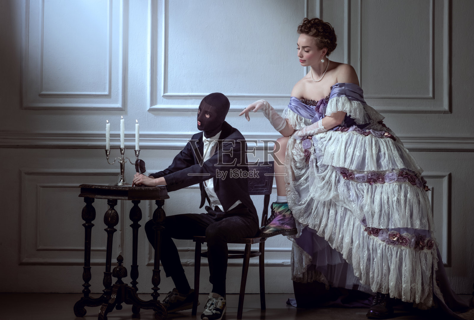 古典复兴风格。年轻美丽的女子在中世纪皇家人物的形象在晚礼服与仆人孤立在黑暗的背景。时代的比较照片摄影图片