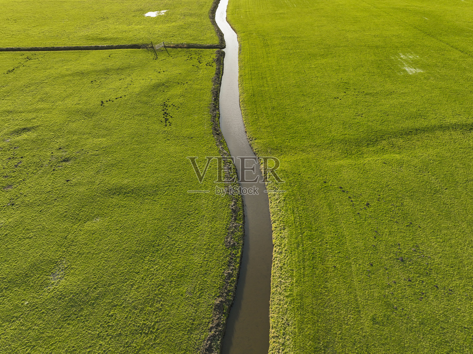 从上面看，沟渠穿过绿色的草地照片摄影图片