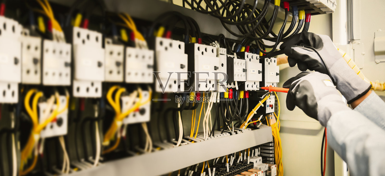 电气工程师用万用表测试电气安装和保护继电器接线。照片摄影图片