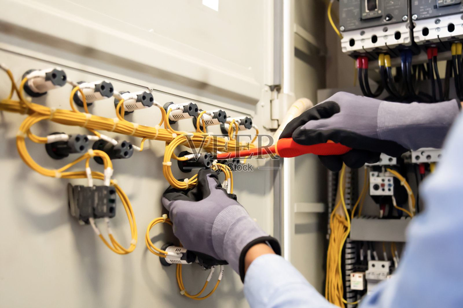 电工在控制柜中负责连接系统、配电板、电气系统中的电线。照片摄影图片