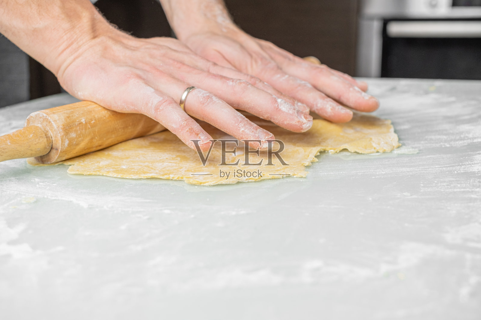 一个男人在家里的桌子上揉面团。照片摄影图片