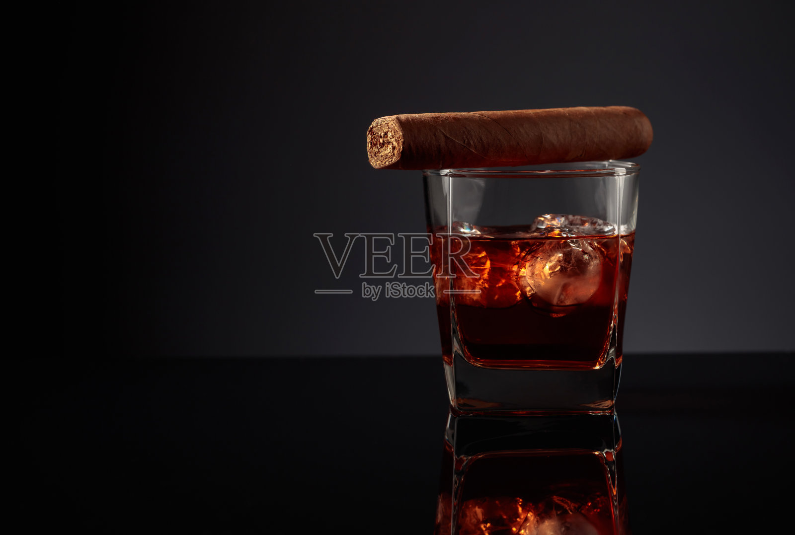 一杯加冰的威士忌和雪茄。照片摄影图片