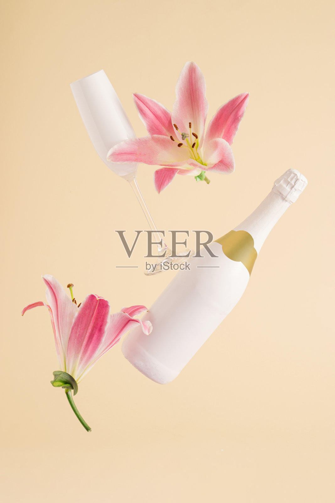 米色背景上漂浮着粉红色花朵的香槟酒瓶和玻璃。最小的情人节或妇女节布局。自然政党概念照片摄影图片