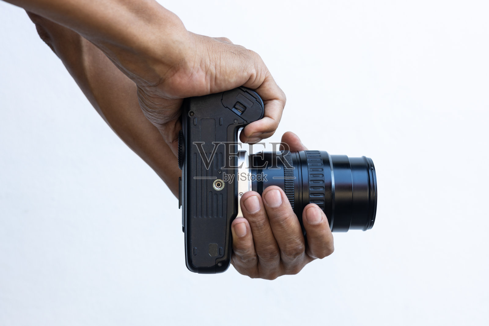 孤立的特写镜头，一个泰国人的手和手指拿着一个旧的黑色单反电影相机。照片摄影图片