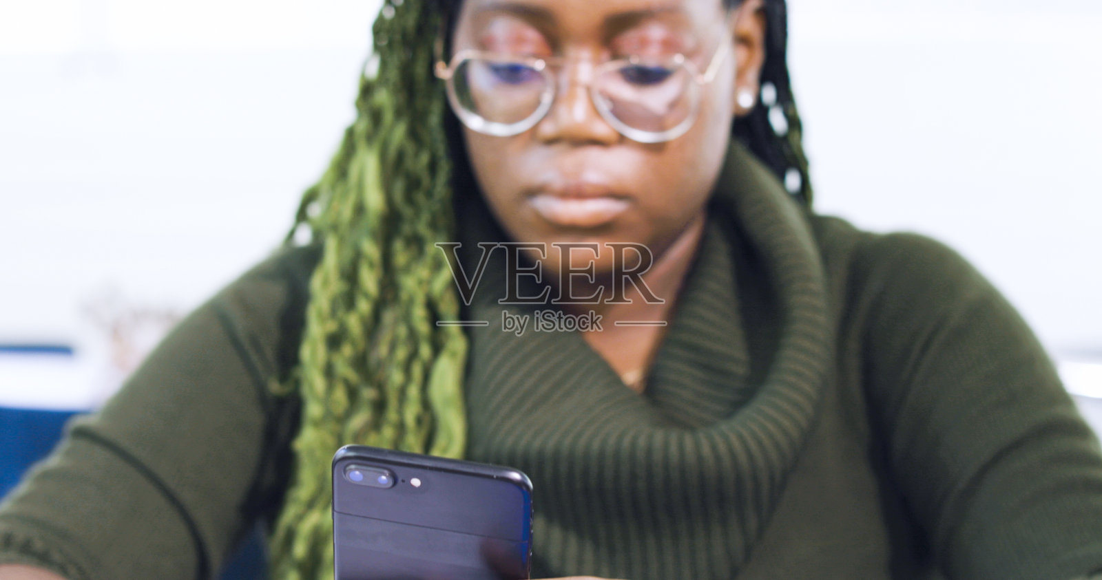 梳着绿色辫子的黑人女人在玩手机照片摄影图片