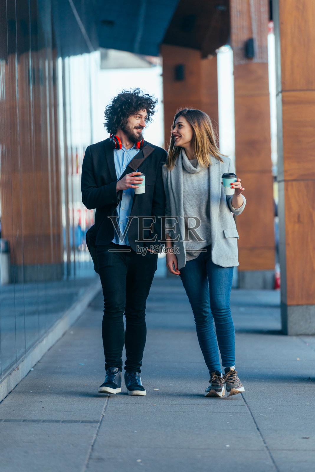 商务夫妇(同事)走在未来的现代车站(机场)，一边喝咖啡，一边聊天。照片摄影图片