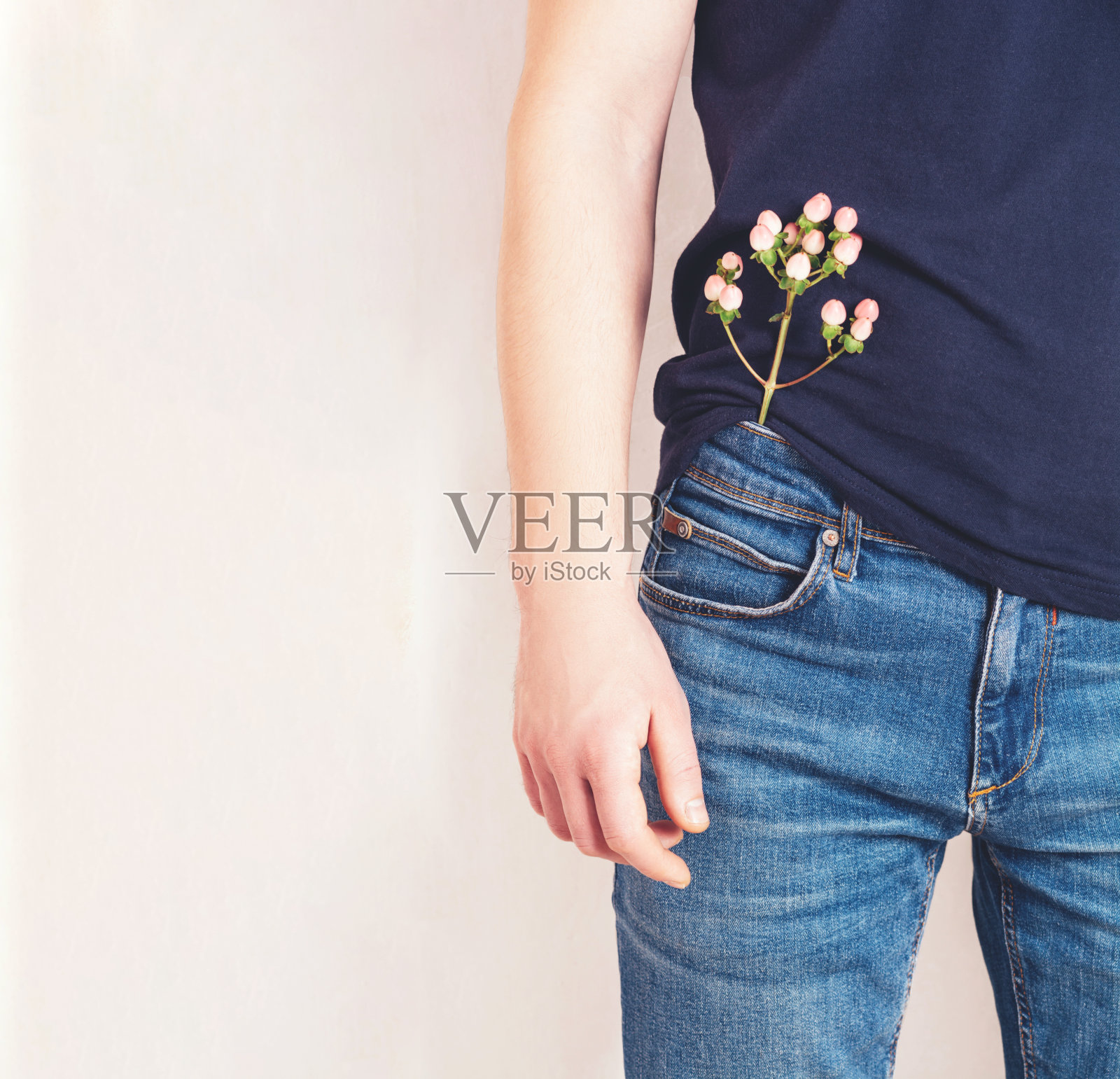 一个穿着t恤，牛仔裤口袋里插着一朵花的男人照片摄影图片