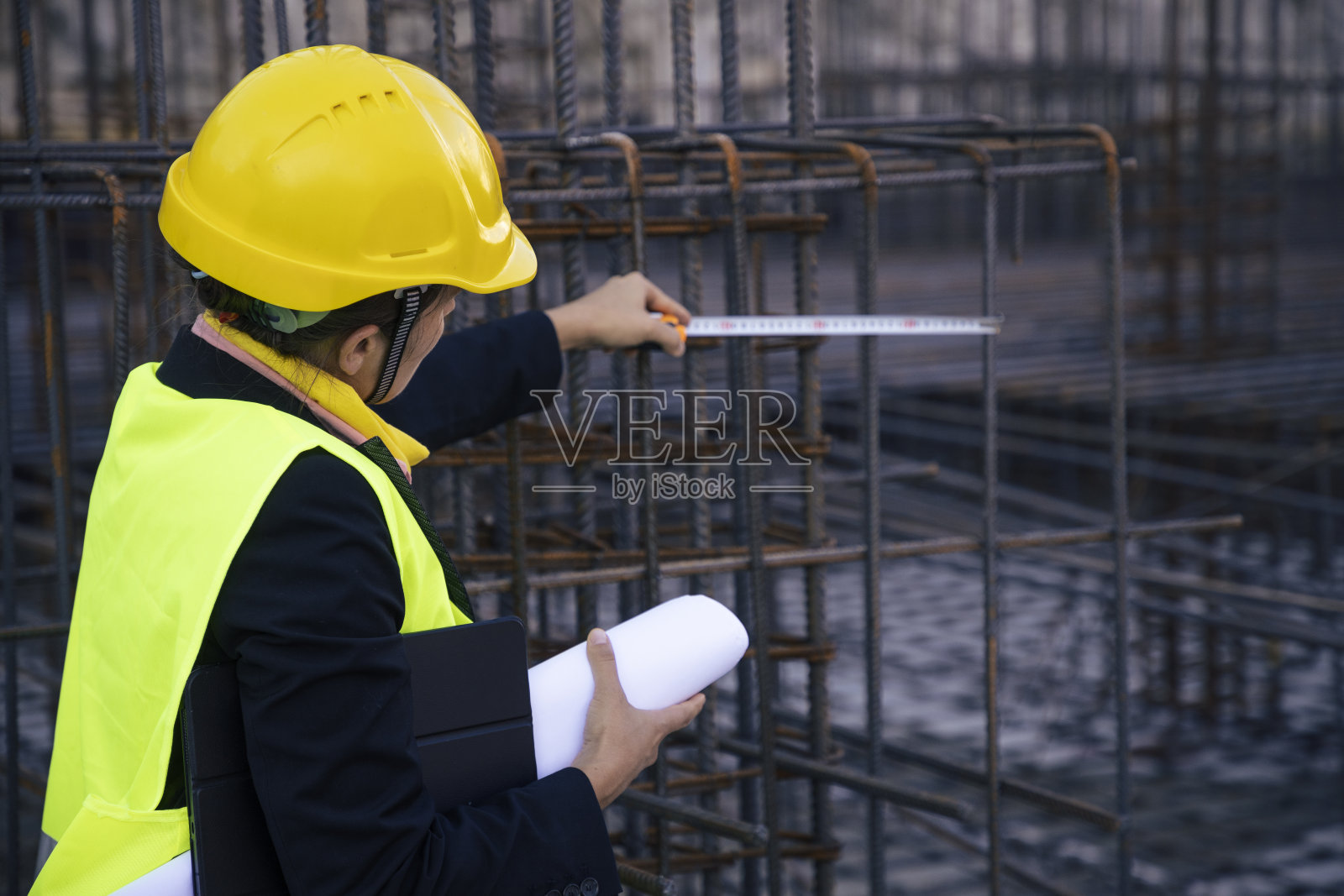 女工程师在工地拿着平板，检查工作进度。测量钢筋。照片摄影图片