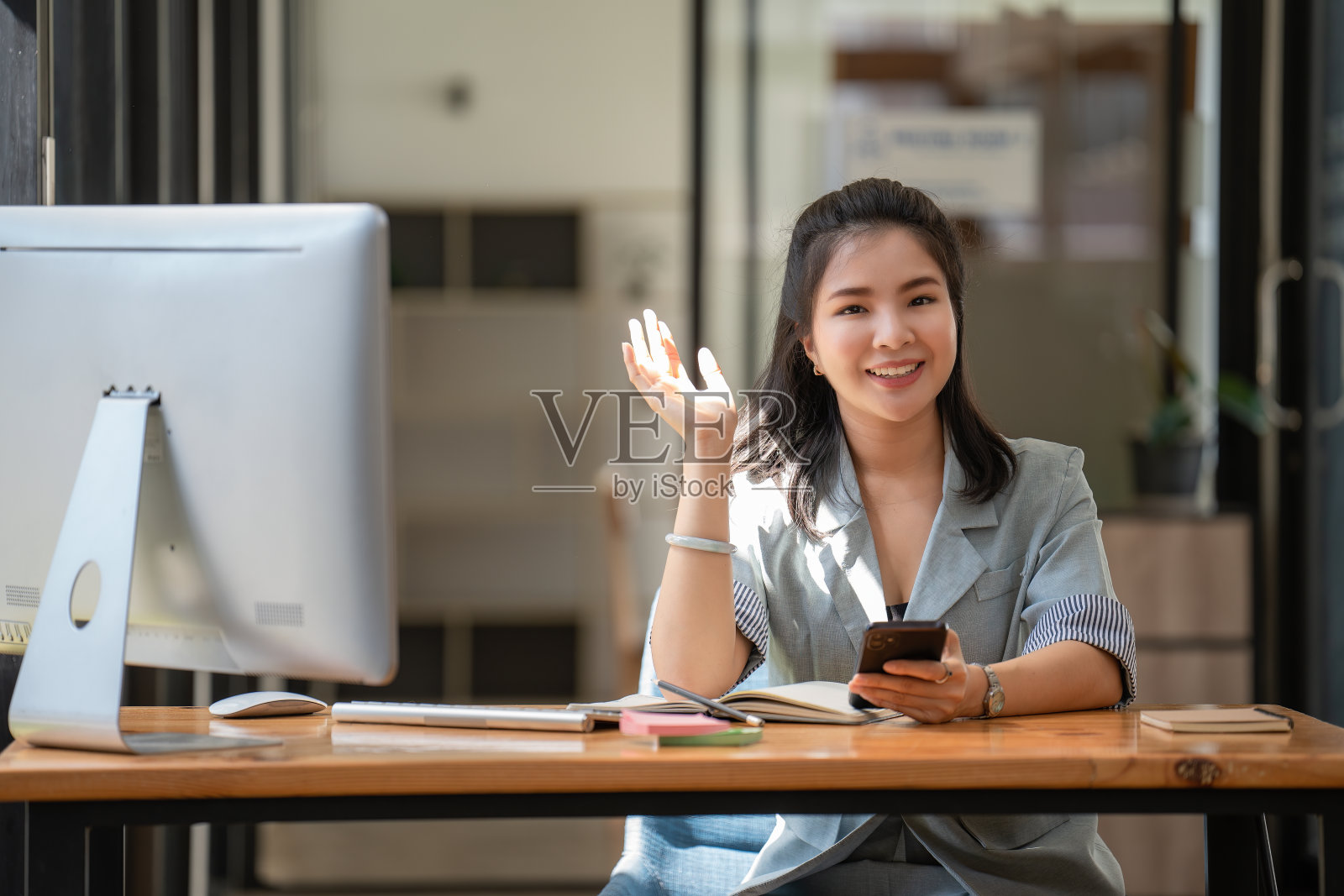 年轻的女商人拿着电话，挥舞着她的手照片摄影图片