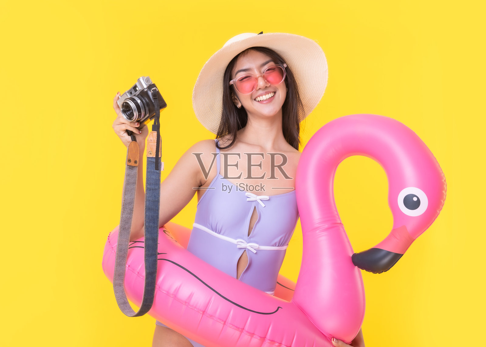 美丽性感的亚洲女人比基尼和微笑站在黄色背景孤立。暑假快乐旅行的概念。照片摄影图片