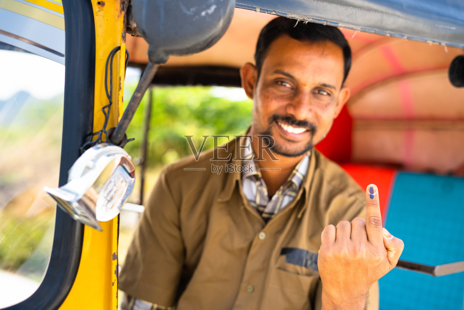 关注手指，微笑的司机在选举投票后看着镜头露出有墨迹的手指——民主、印度选举和责任的概念照片摄影图片