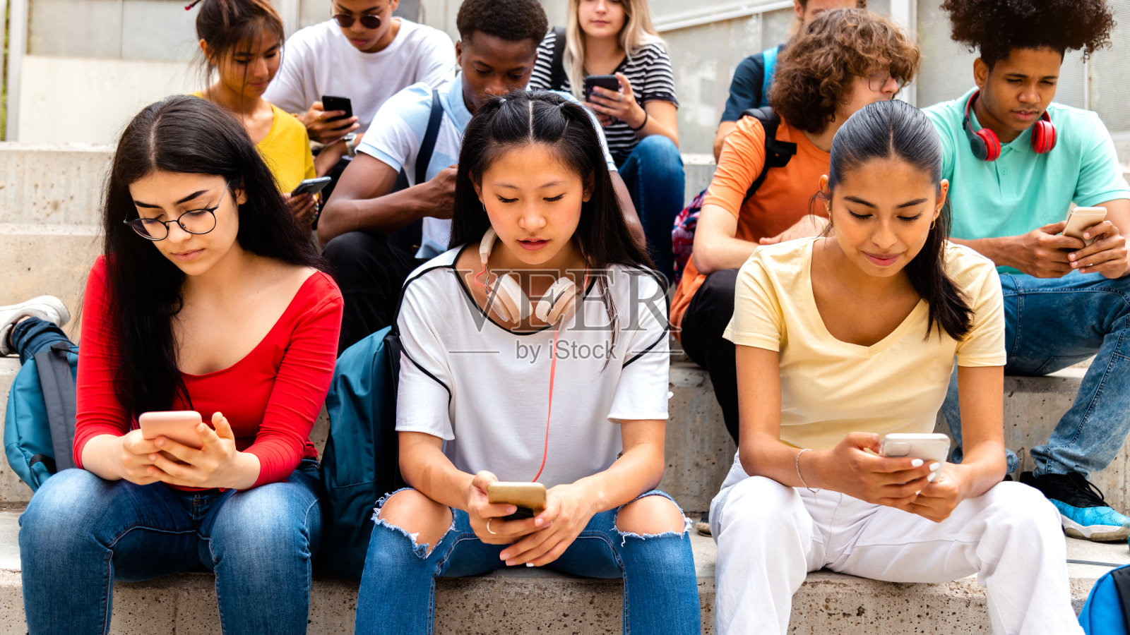 一群多种族的高中生用手机互相忽视。沉迷于社交媒体照片摄影图片