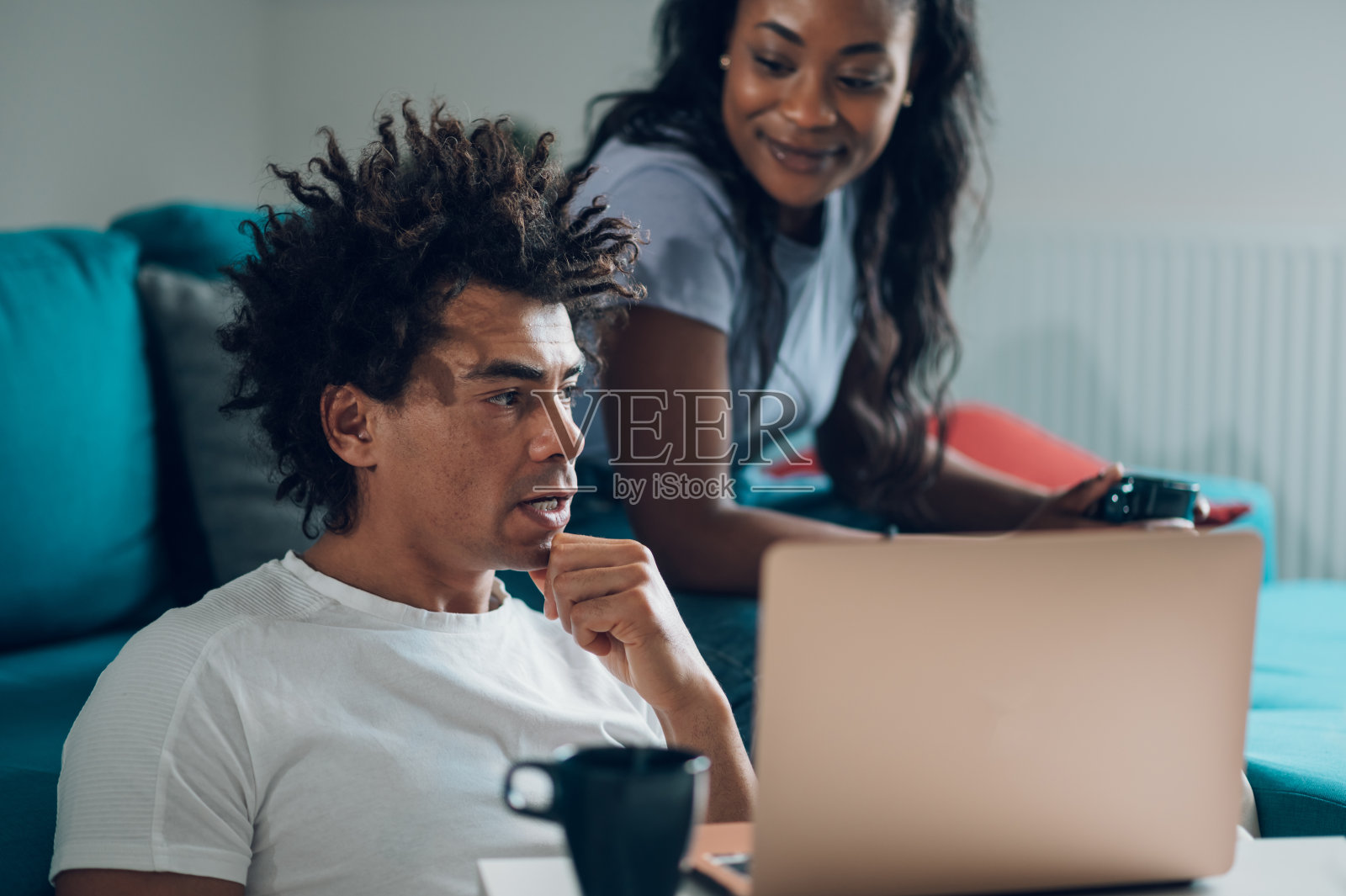 一对非洲裔美国夫妇在家里的沙发上放松着笔记本电脑和咖啡照片摄影图片