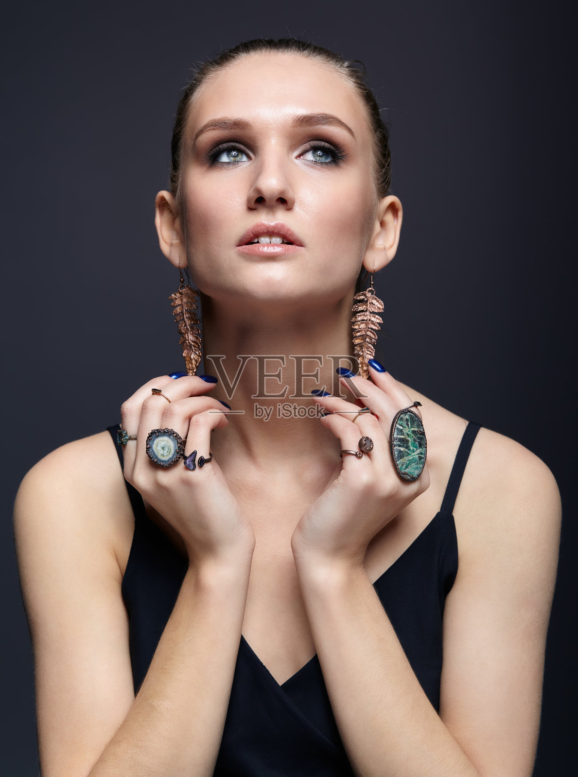 年轻女子，手指上戴着许多宝石戒指照片摄影图片