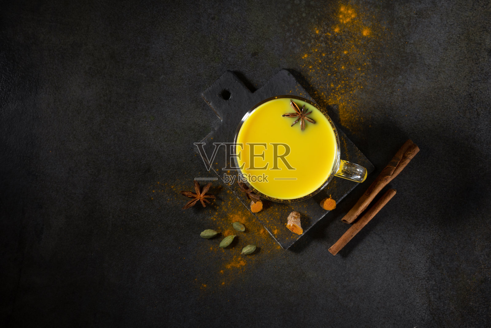 一杯金色牛奶，姜黄粉，新鲜的姜黄根，茴香和肉桂。香料和药草的概念。阿育吠陀酒在浅色的背景下。空间的文本。照片摄影图片