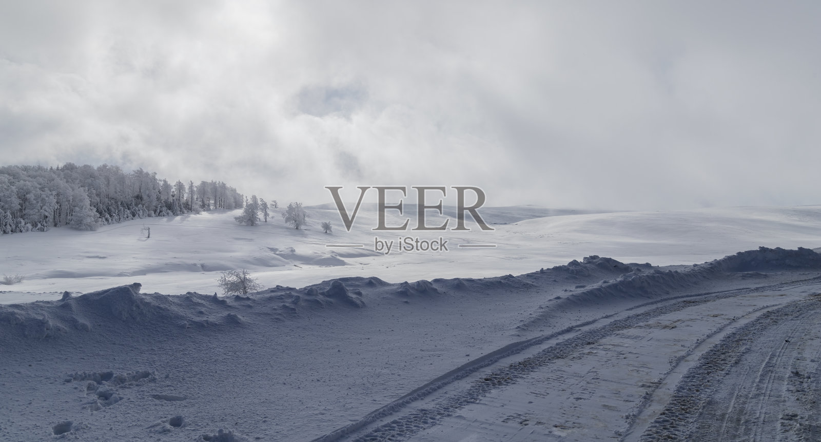 在罗马尼亚的一座山顶上，一条冰冻的道路和远处阳光下的森林照片摄影图片