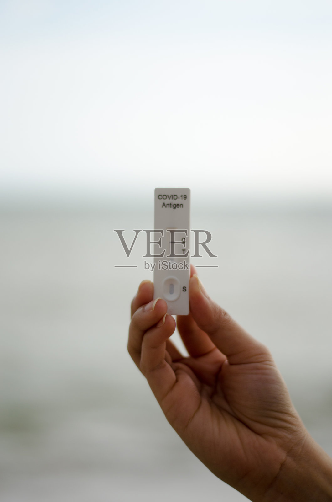 在COVID-19拭子检测中，手持快速抗原检测试剂盒呈阴性的妇女。照片摄影图片